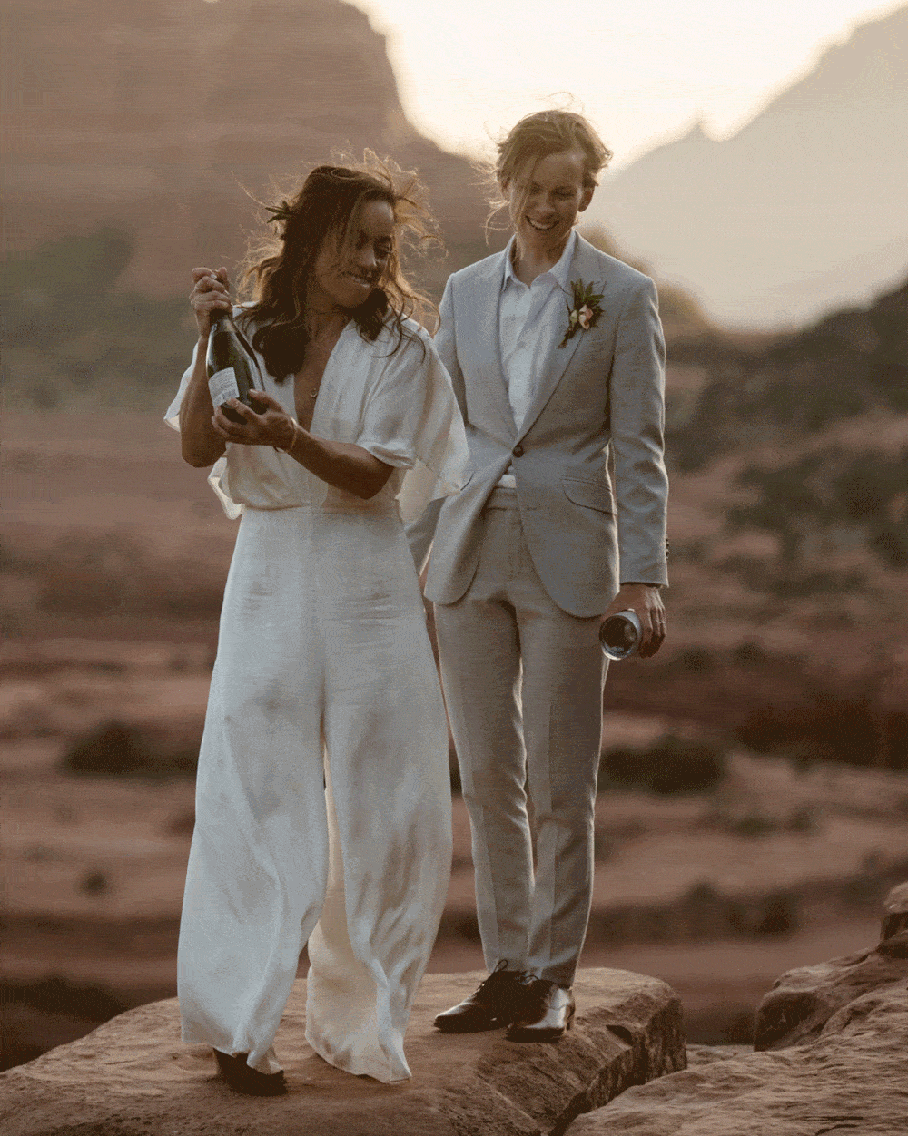 A couple spraying a bottle of champagne in Sedona during sunset.