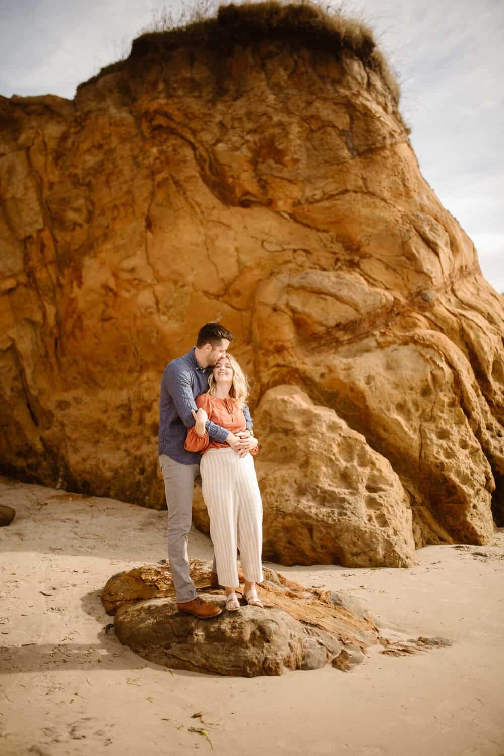 A man holds his woman and kisses her forehead.