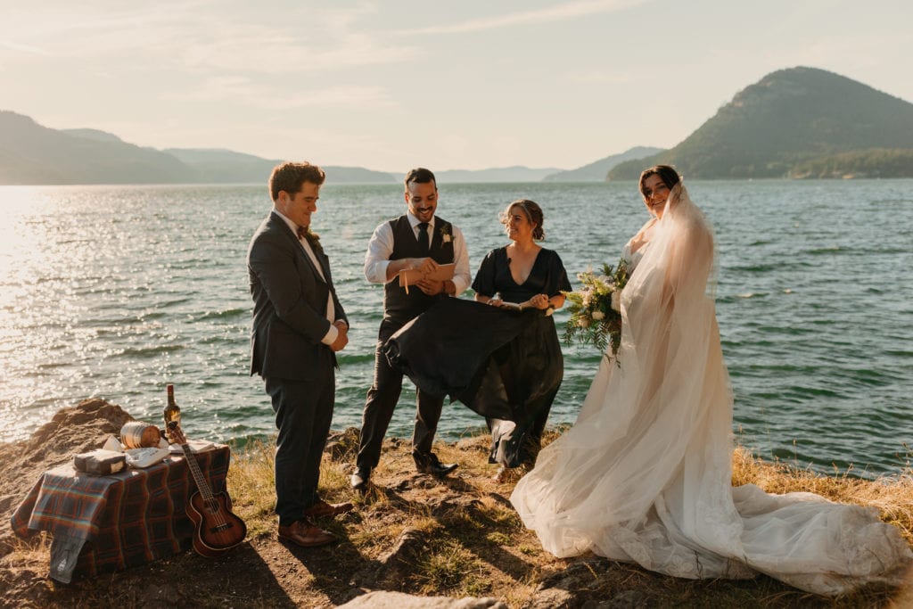 A bride and groom stand together as their friends both officiate their wedding.