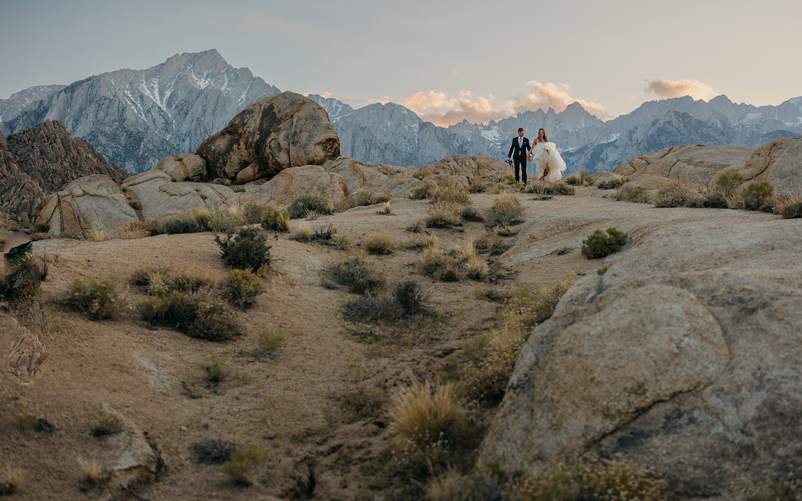 A couple walks in the desert mountains together at blue hour.