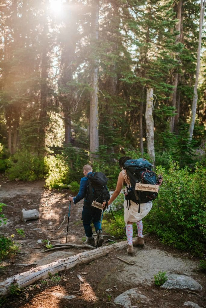 A couple walks together with wedding signs through the forest