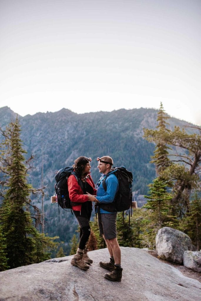 A couple stands together taking a break while hiking in the mountains