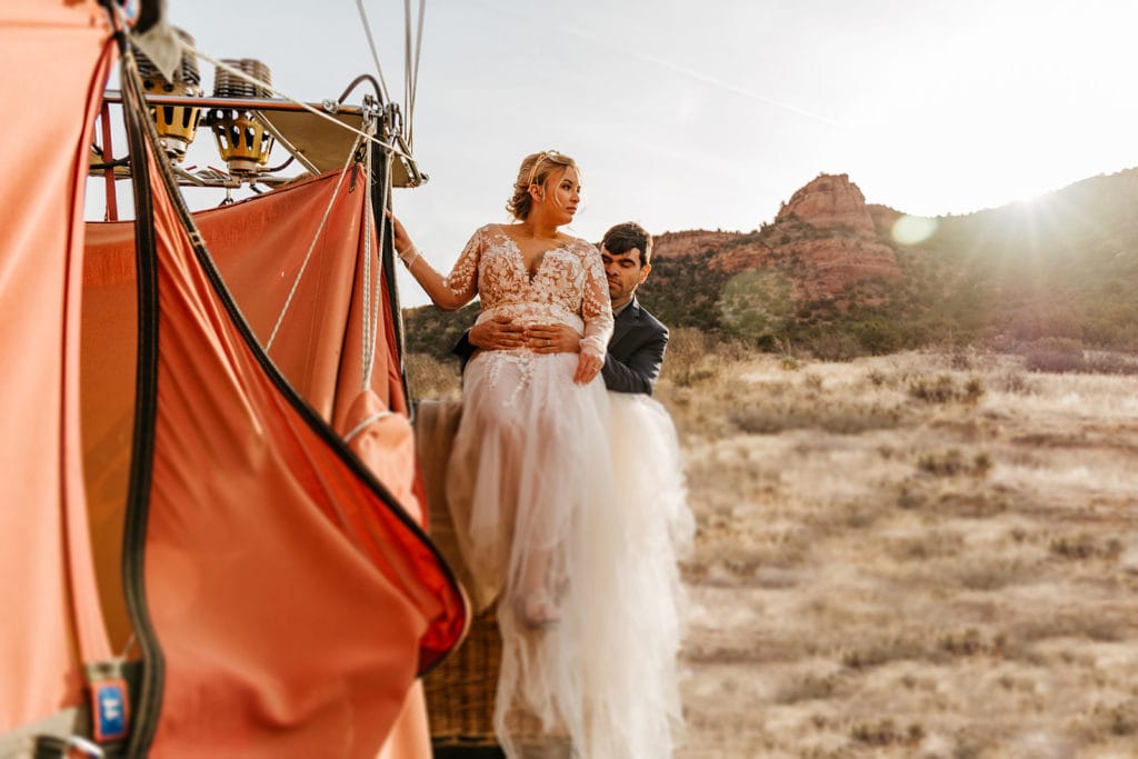 A couple sits on the side of a hot air balloon together after a sunrise ride over Sedona.