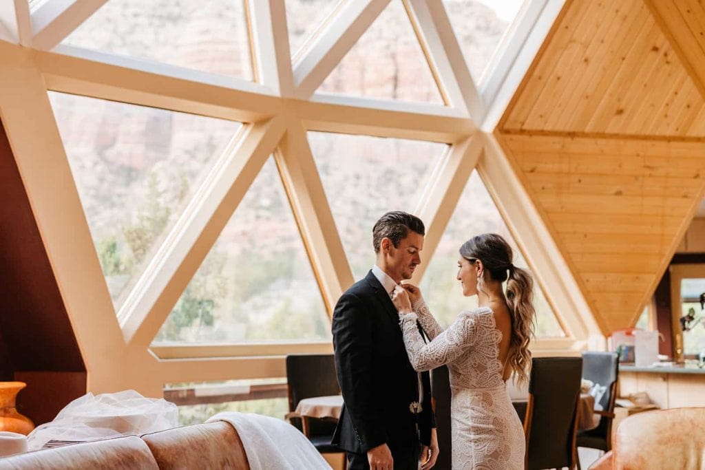 A bride helps her groom as he gets ready for the day ahead.