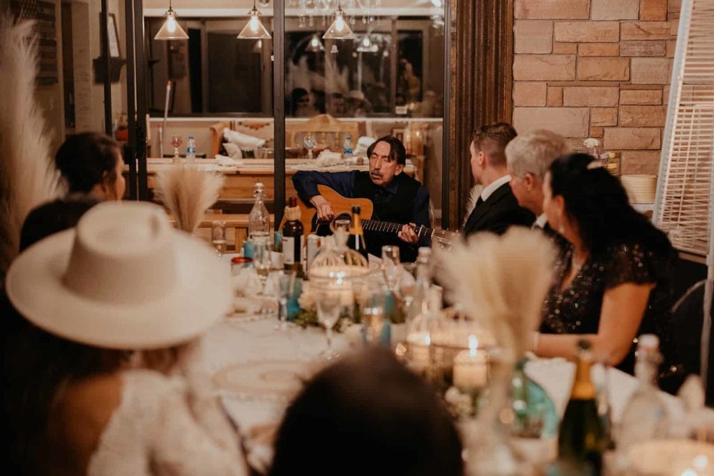 A father playing guitar for the family and bride and groom.