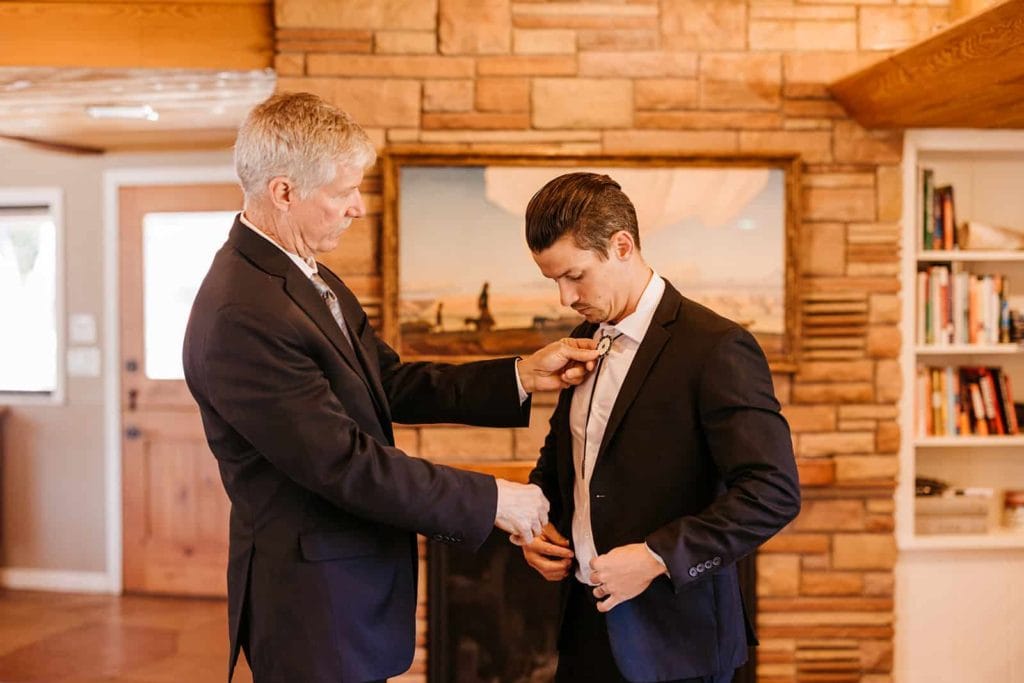 A father helps his son put on a tie.
