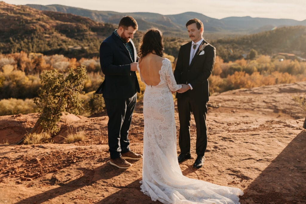A bride and groom holding hands while an officiant performs their ceremony.