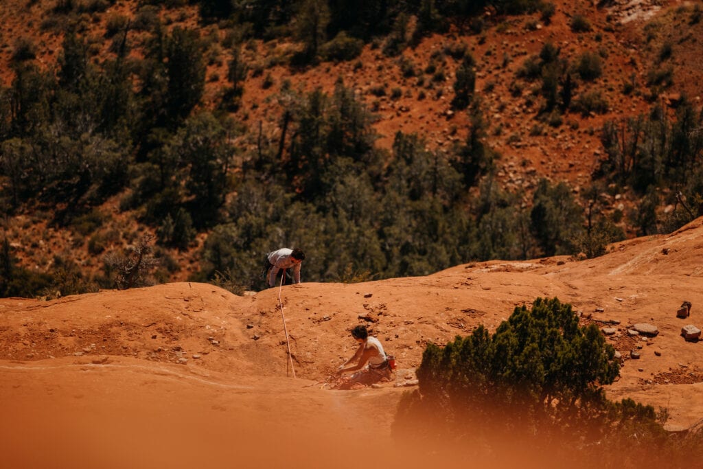 A high up shot of a bride belaying her groom up to the belay station in Sedona