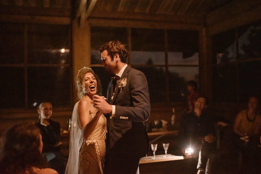 A bride and groom sharing a dance together inside at night.