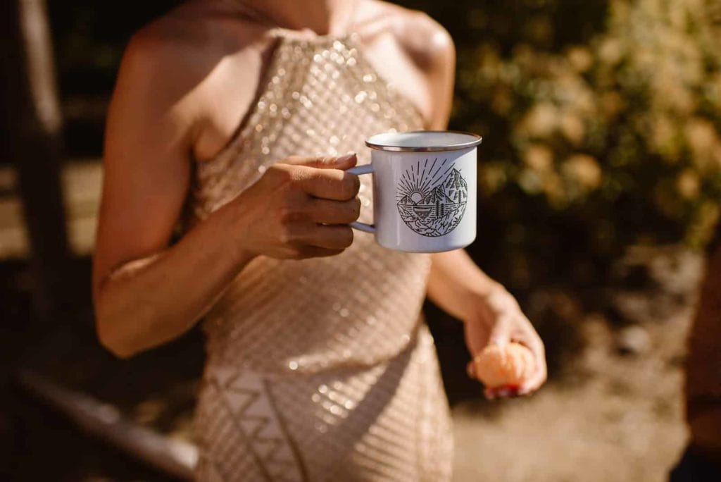 Someone holding a mug that has a decal of mountains and the sun in a cartoonish fashion.
