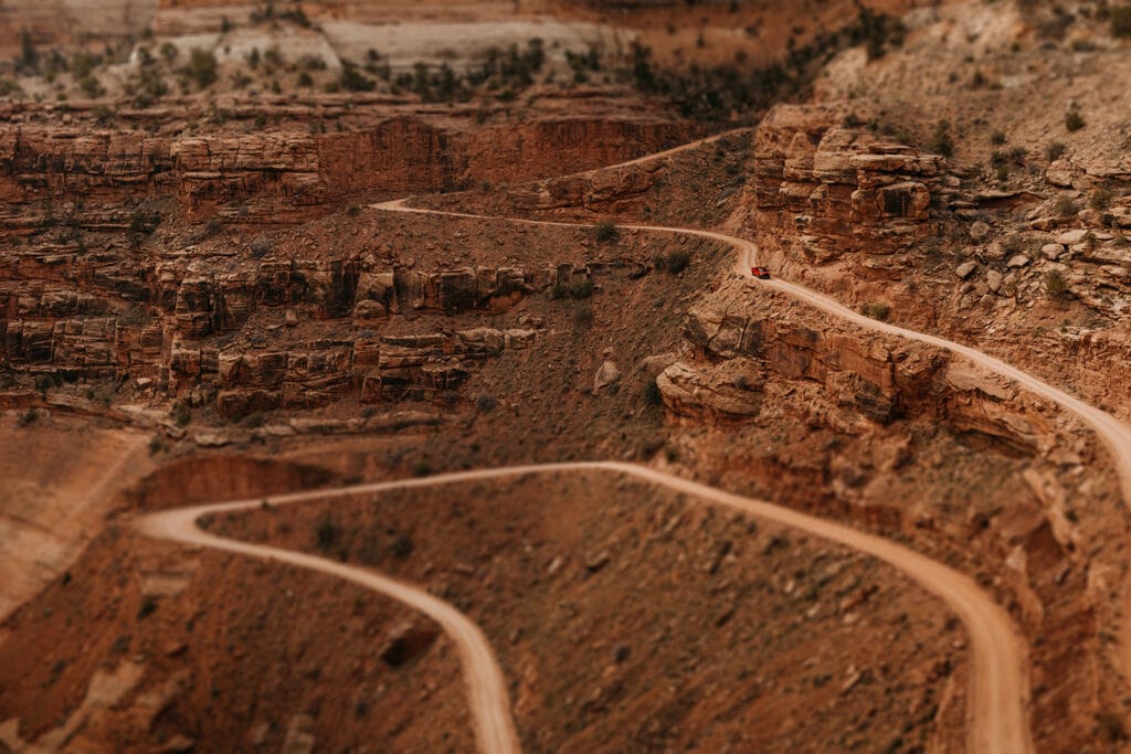 A couple drives Shafter Trail road in Canyonlands National Park.