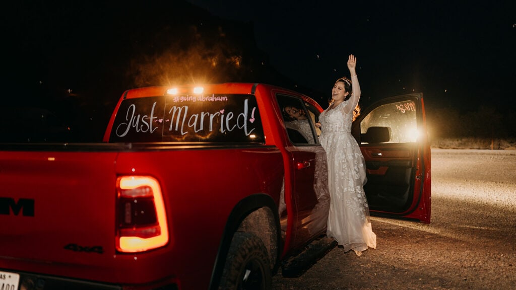 The bride waves goodbye from the truck