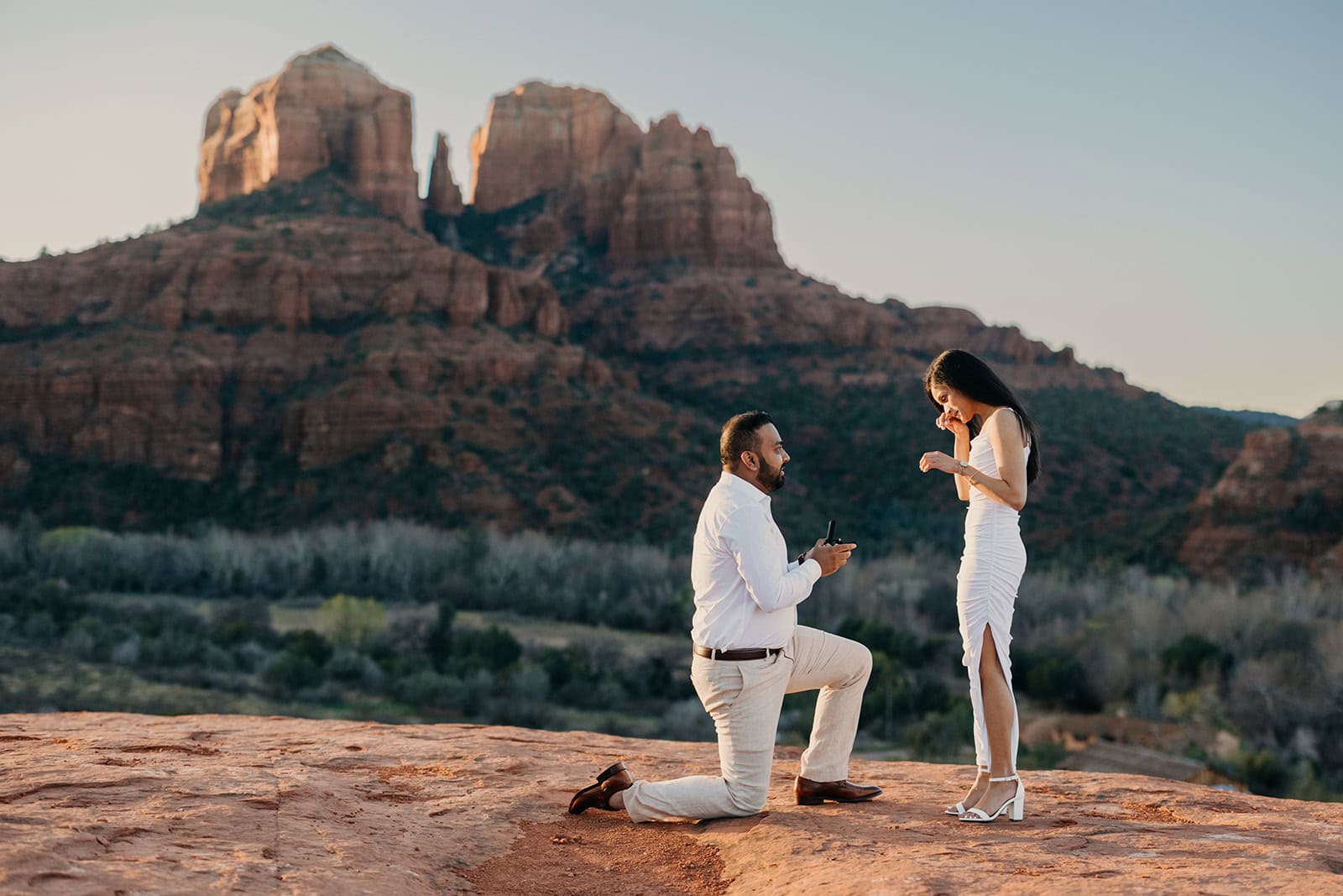 A groom proposes to his partner as she wipes her tears away in the morning sunlight in Sedona.