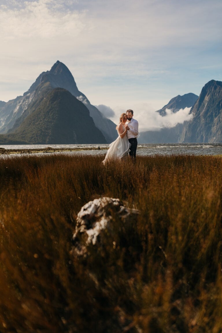 A bride and groom hold each other at Milford sound.