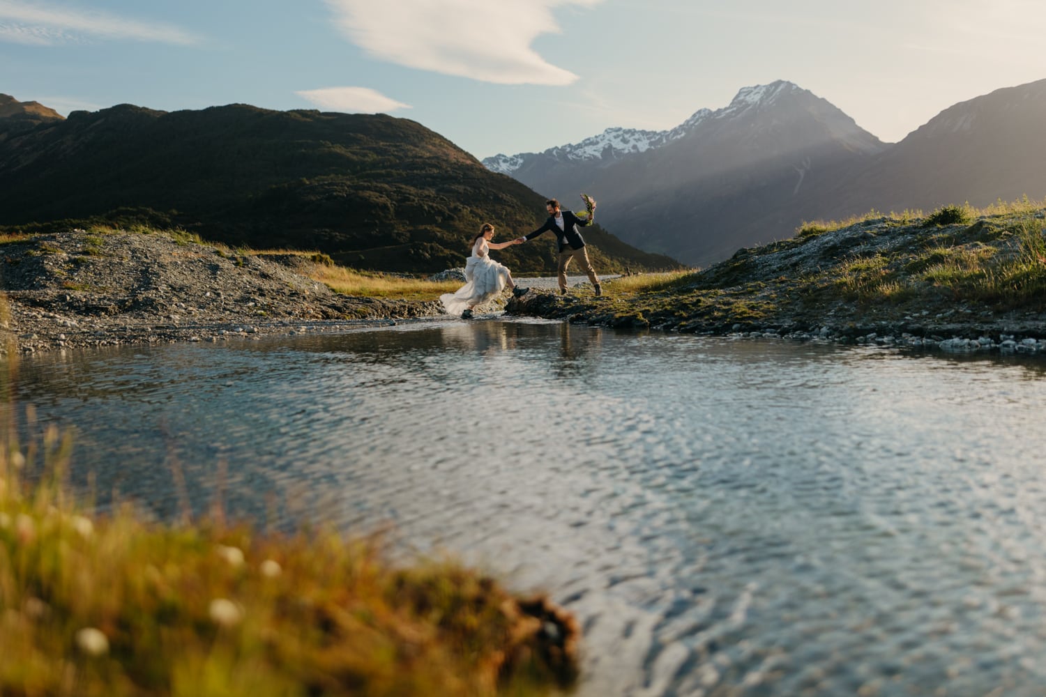 A bride and groom cross over the river together to get to their ceremony location.
