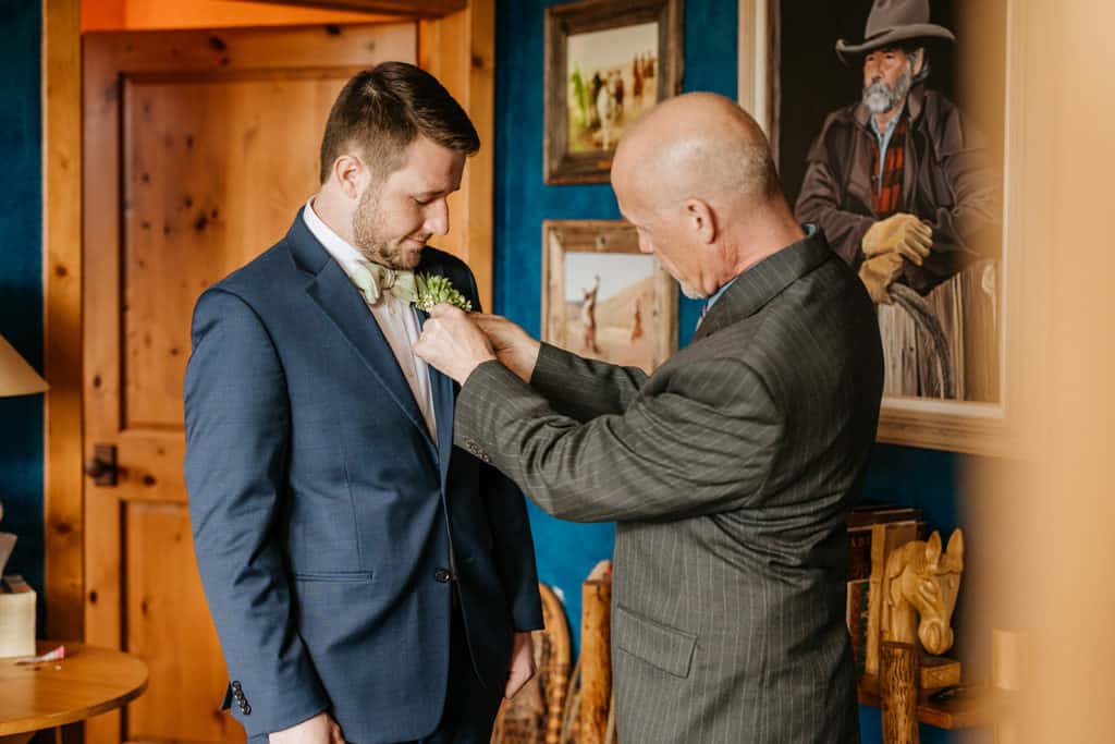 A father helping his son with his boutonniere. 
