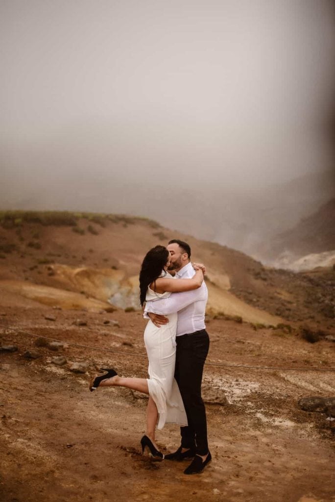 A groom holds his bride for a kiss on a rainy foggy day in Iceland.
