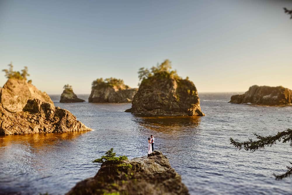 a couple on a rock in the middle of the Oregon coast.