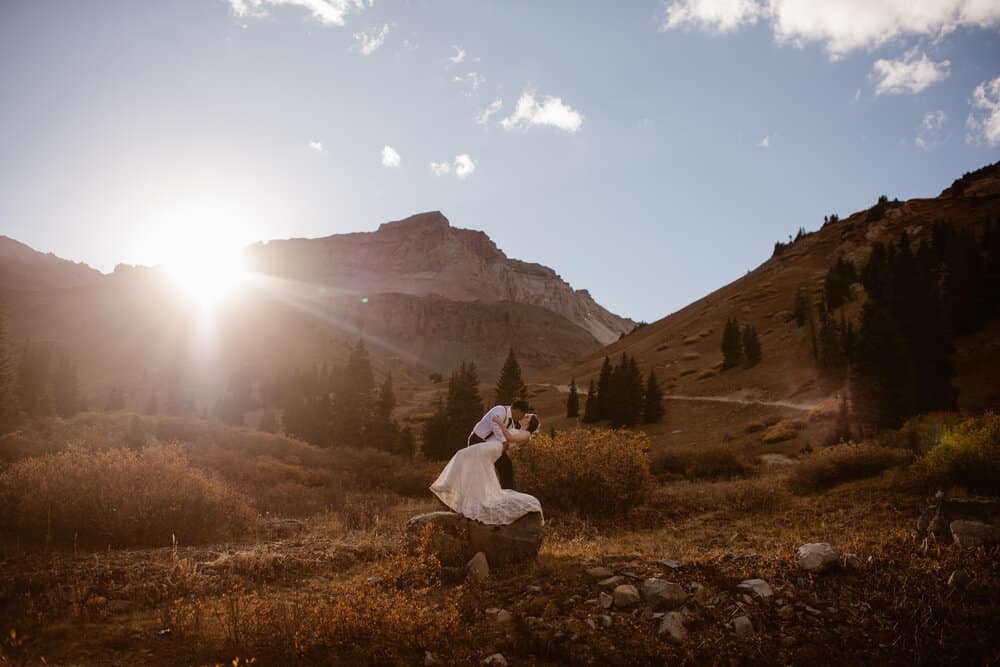 A sunset image of a couple sharing a kiss in the mountains.