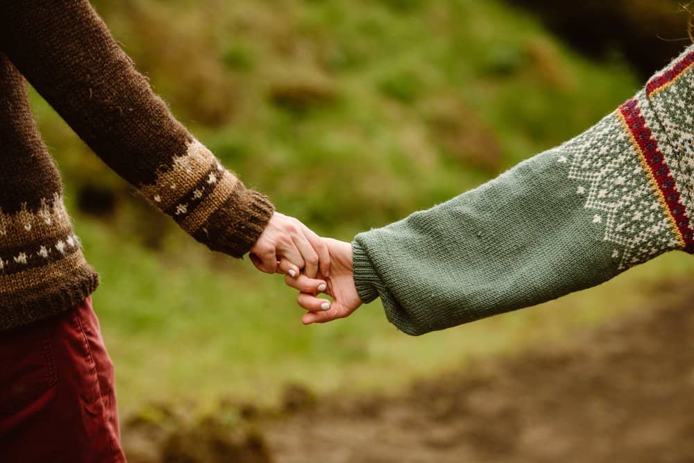 A close up images of the couples hands as they hold each others.