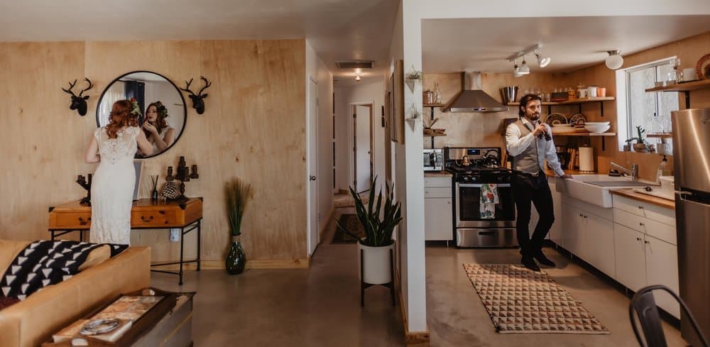 A couple gets ready for their elopement day in an airbnb on different sides of the house.