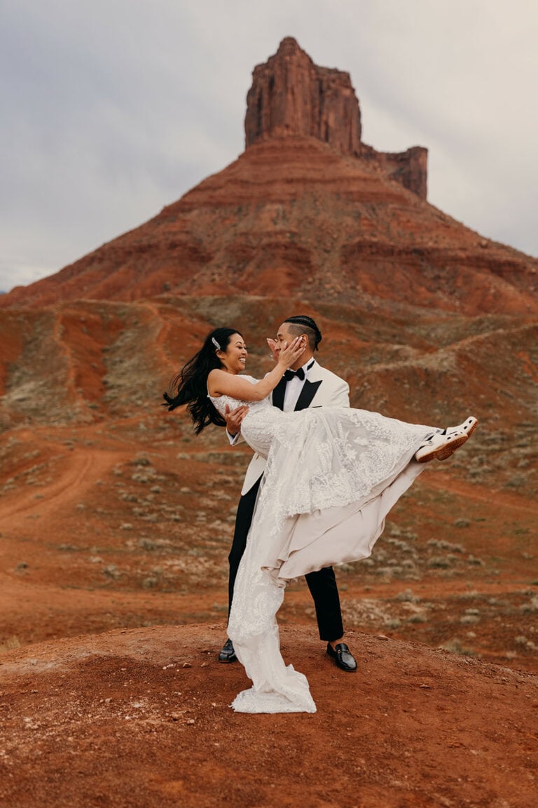 The groom twirls the bride around as he picks her up.