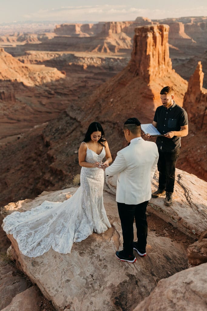 The bride puts the ring on the grooms fingers.