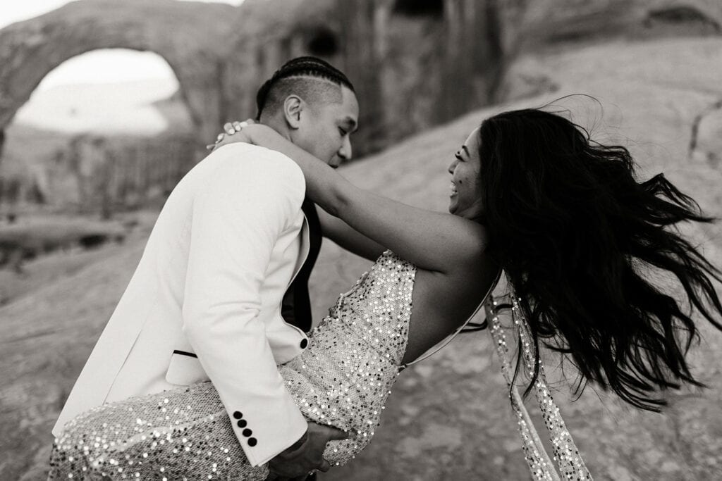 The groom swings the bride around as she wraps around him.