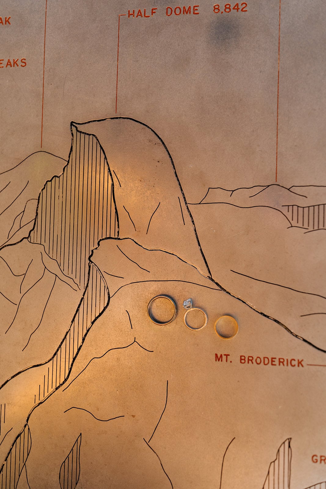 A detail photo of the couples rings on a metal map showcasing the peaks from Glacier Point.