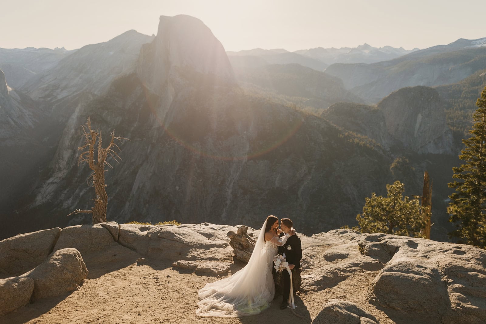 A couple holds each other overlooking Half Dome in Yosemite from Glacier Point.