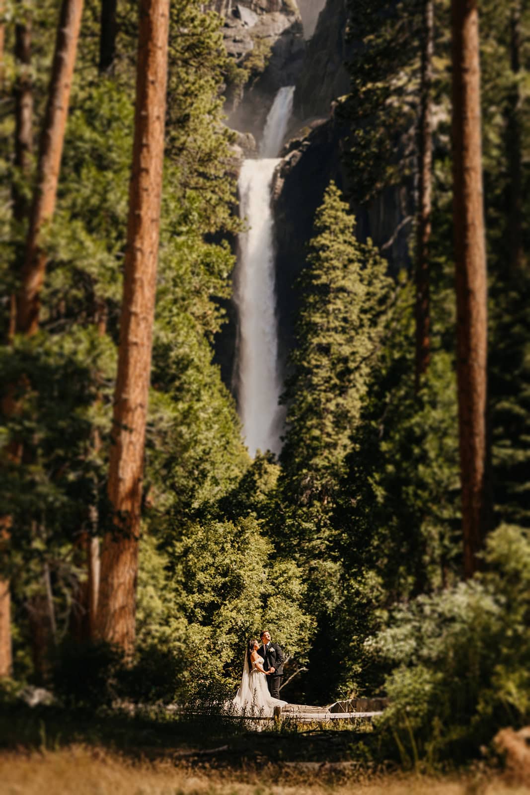 A couple stands at the base of Lower Yosemite Falls on a spring day.