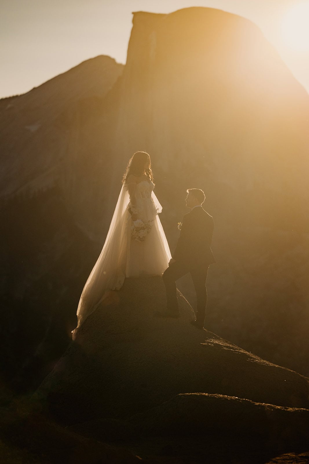 A couple stands in the morning sunlight at Glacier Point on their elopement day in Yosemite.