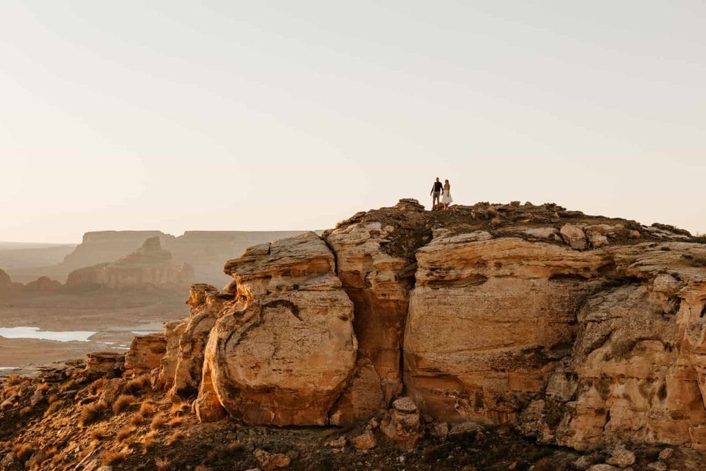 A bride and groom stand together on a distant viewpoint
