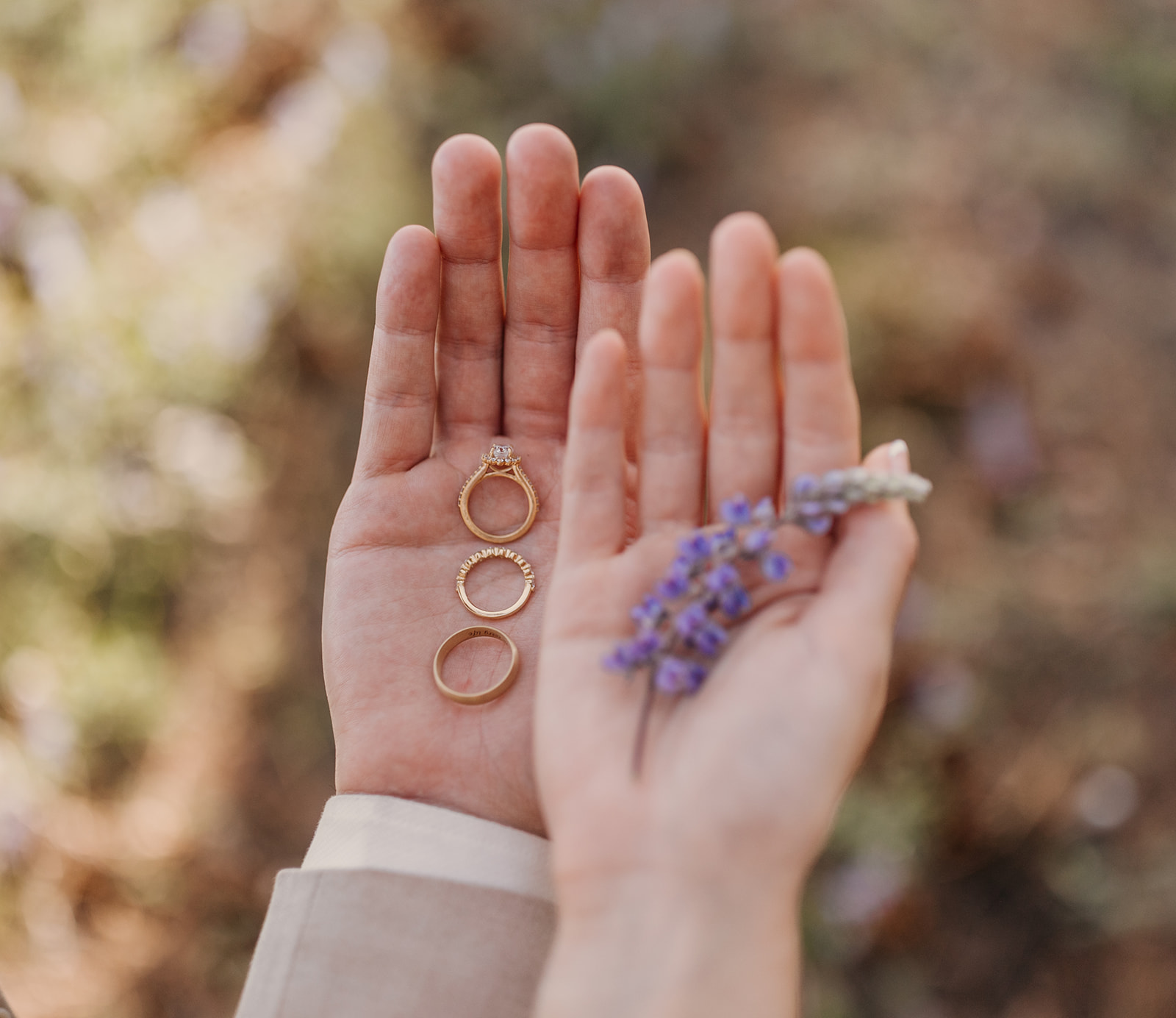 A detail photo of the couples rings while the bride holds a lupine.