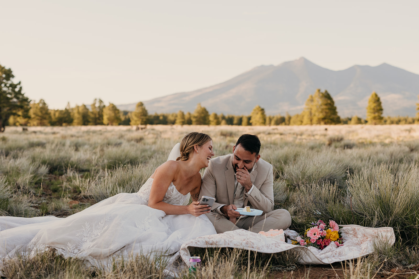 A couple smiles and laughs as they watch a surprise wedding video from their friends.