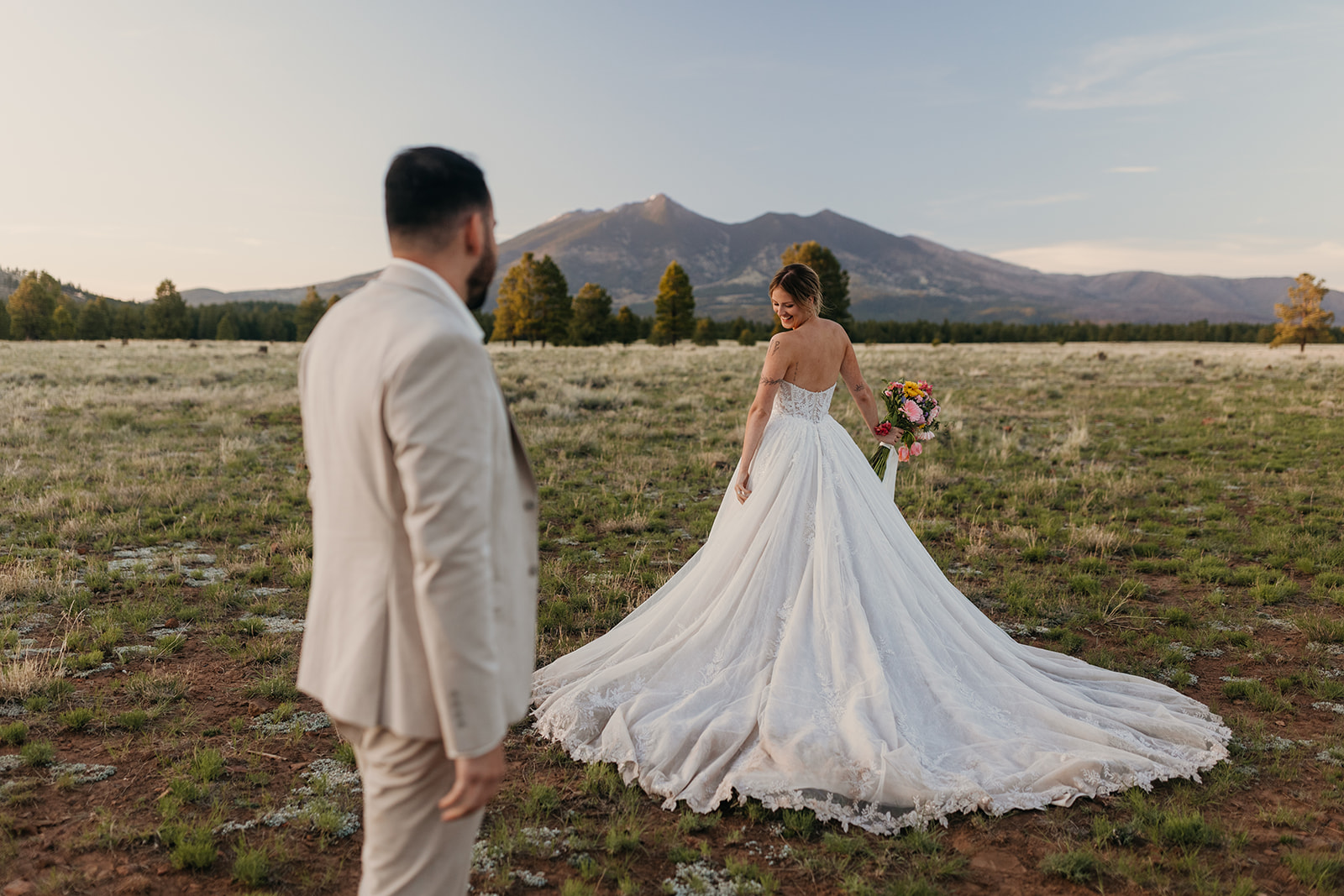 A bride shows off her wedding dress to her groom.