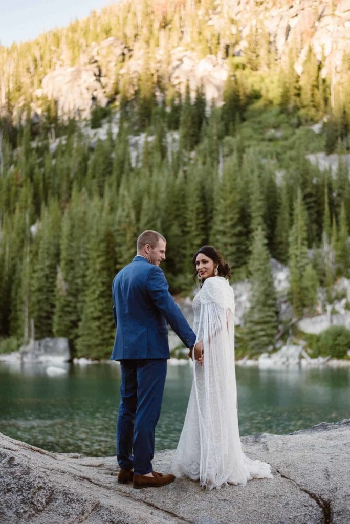 A bride looks back at the camera in the mountains.