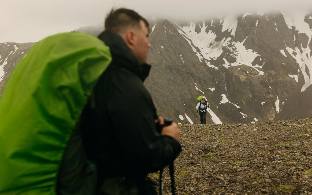 The groom waits for the bride as she finishes the steep incline.