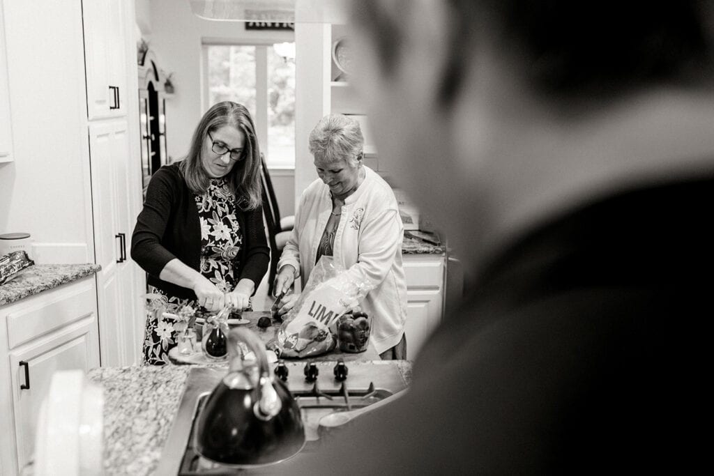 The brides mom and and grand ma cook together in the kitchen.