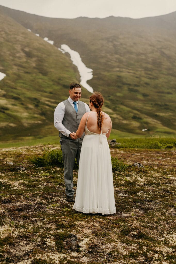 The groom smiles as he sees the bride in her dress.