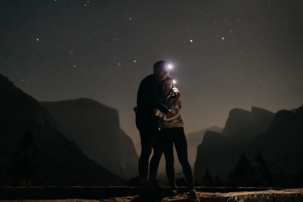 An image of a couple hugging at the end of their hike in Yosemite at 1am. 