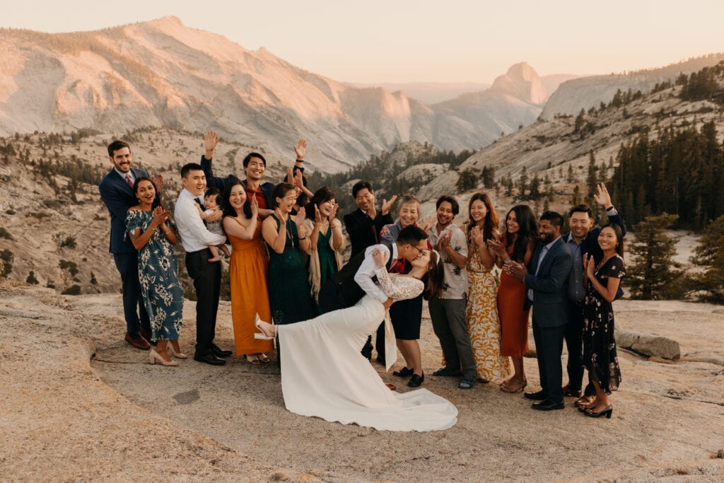 A groom dips kisses bride as the family and friends cheer them on. 