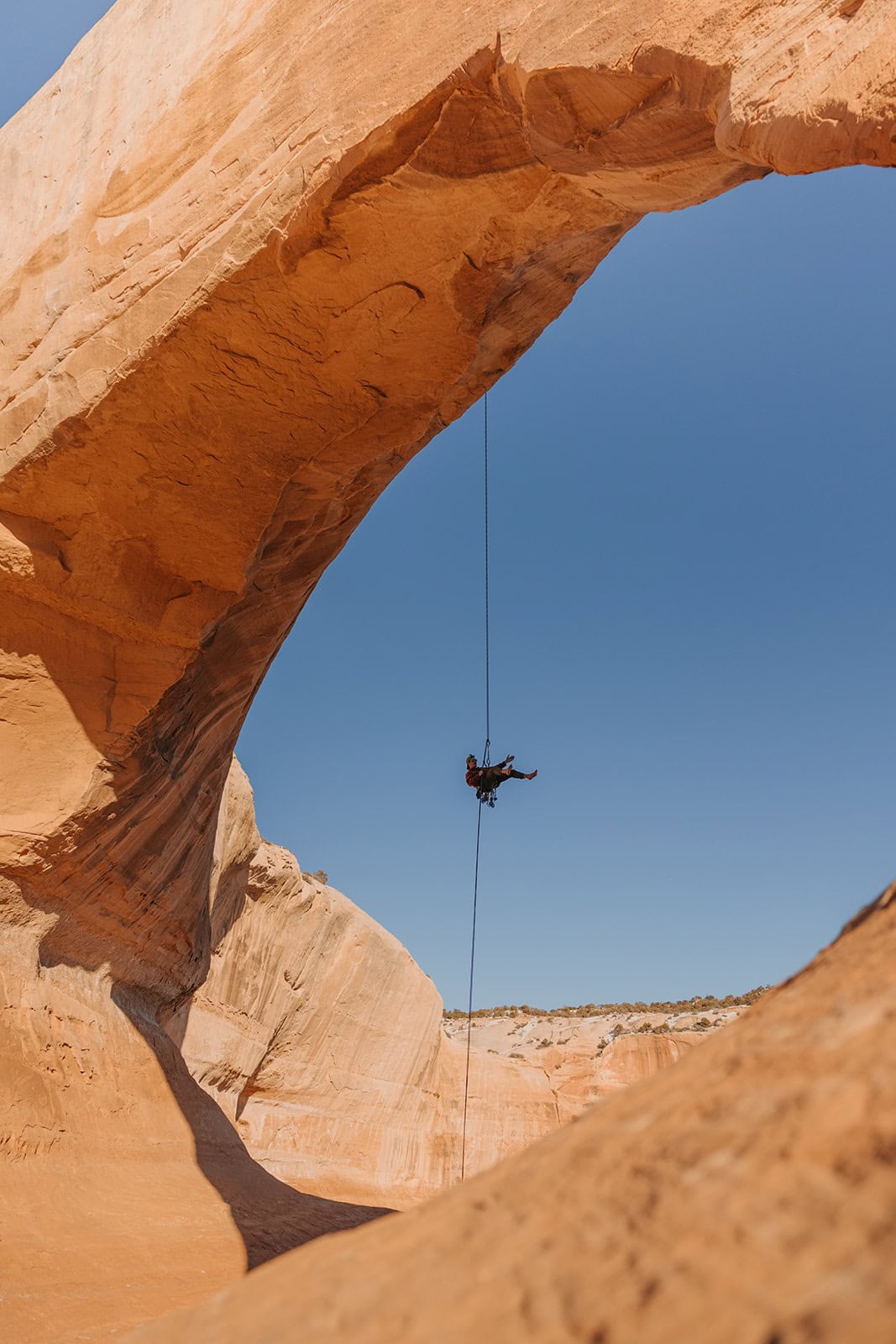 Someone rappelling down an arch outside of Arches National Park