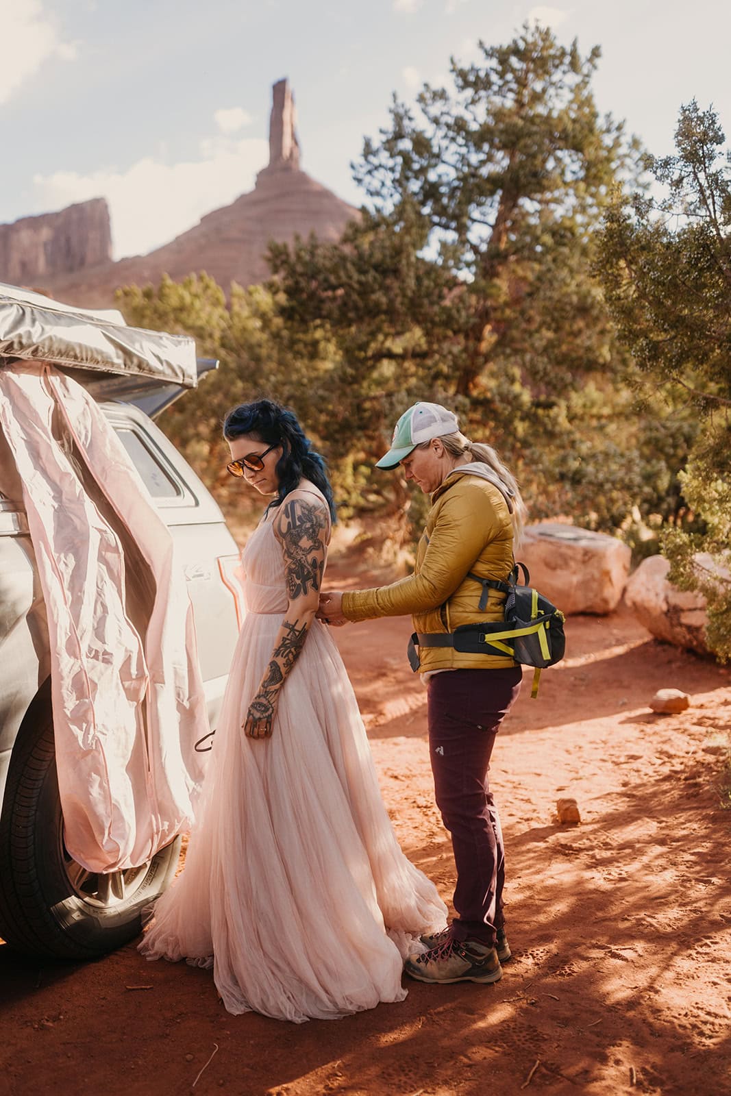 A makeup artist helps a bride on location with her dress.