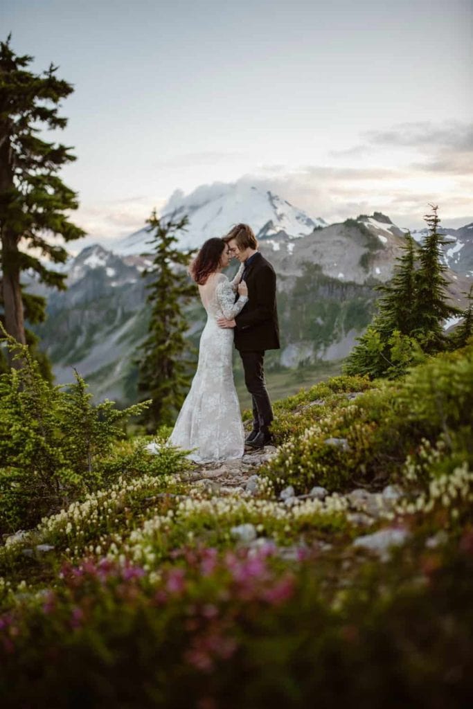 A couple holds each other in the mountains on a summer evening after getting married