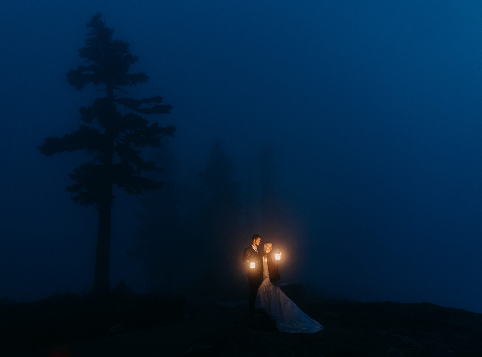 A couple holds lanterns on a thick foggy day in the pnw mountains on their elopement day.