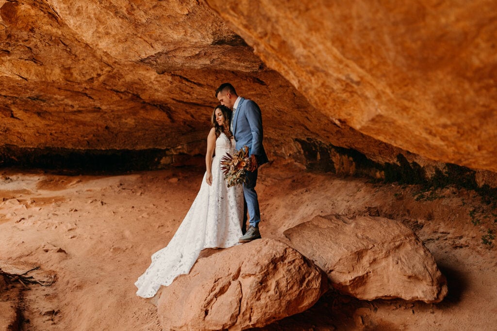 A couple stands on top of a rock together in Zion National Park.