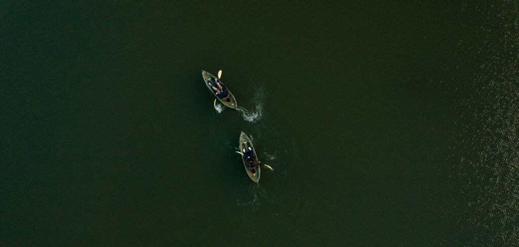 A drone photograph of a bride and groom kayaking together.