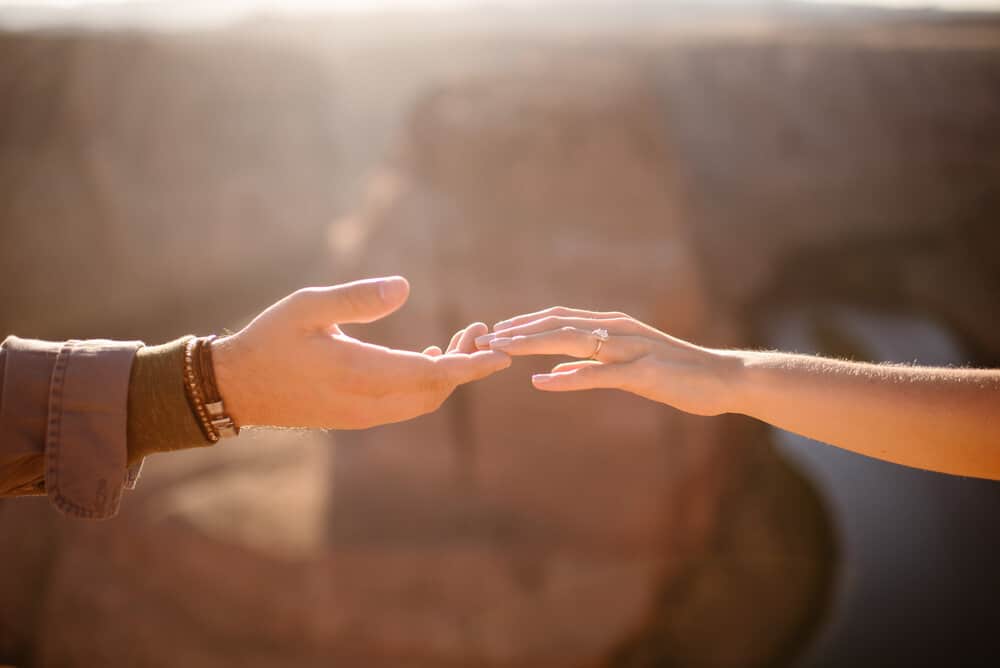A couples hands showcasing the engagement ring.