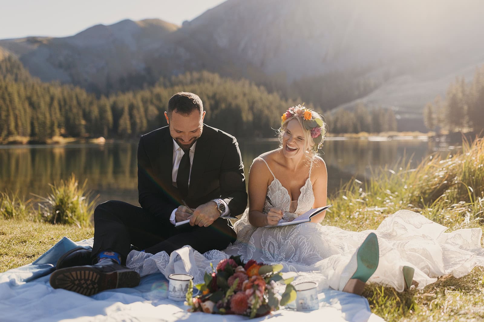 A couple sits together as they write their vows by a lake in Colorado.